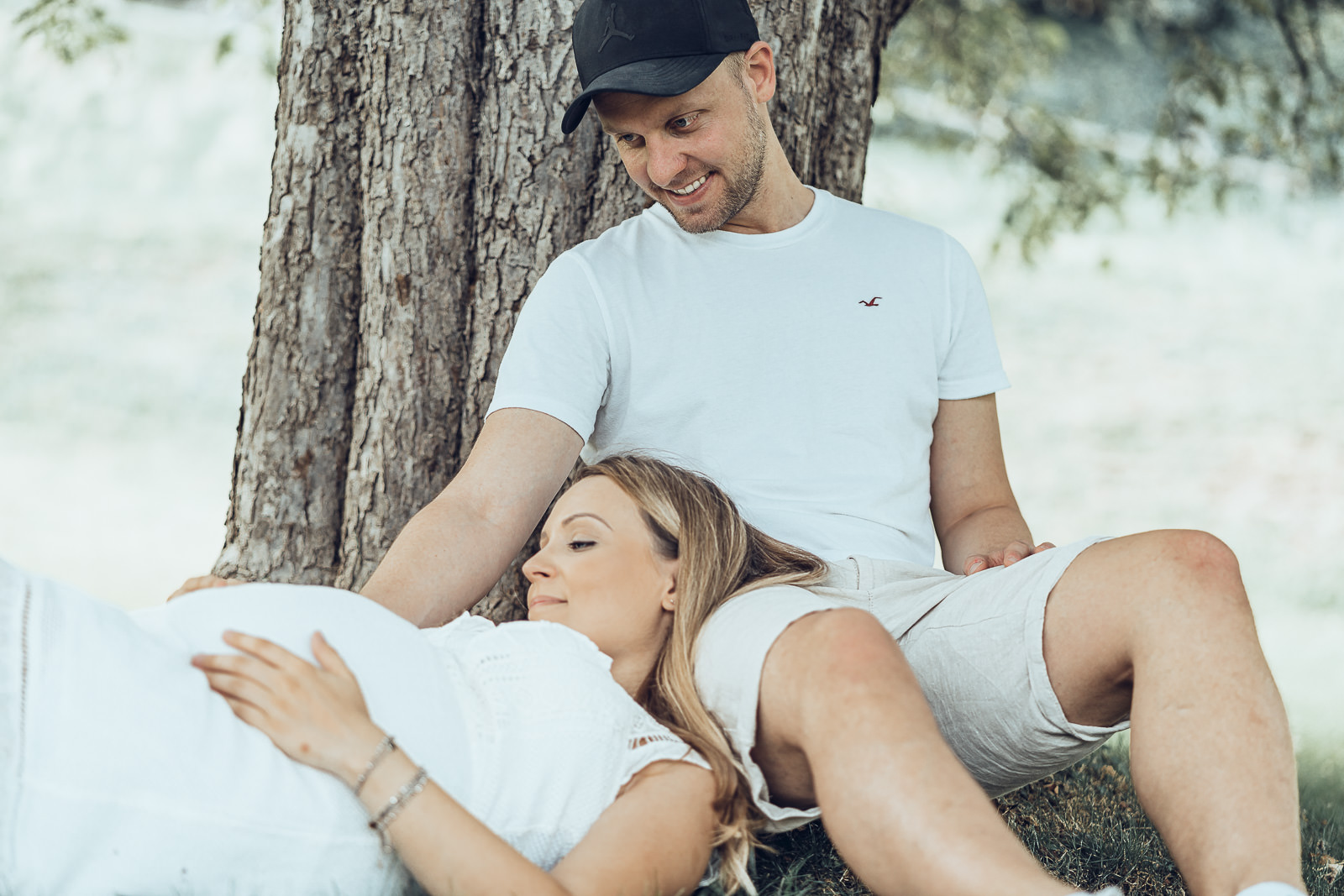 Babybauchfotografin Weiz, werdende Eltern liegend bei einem Baum