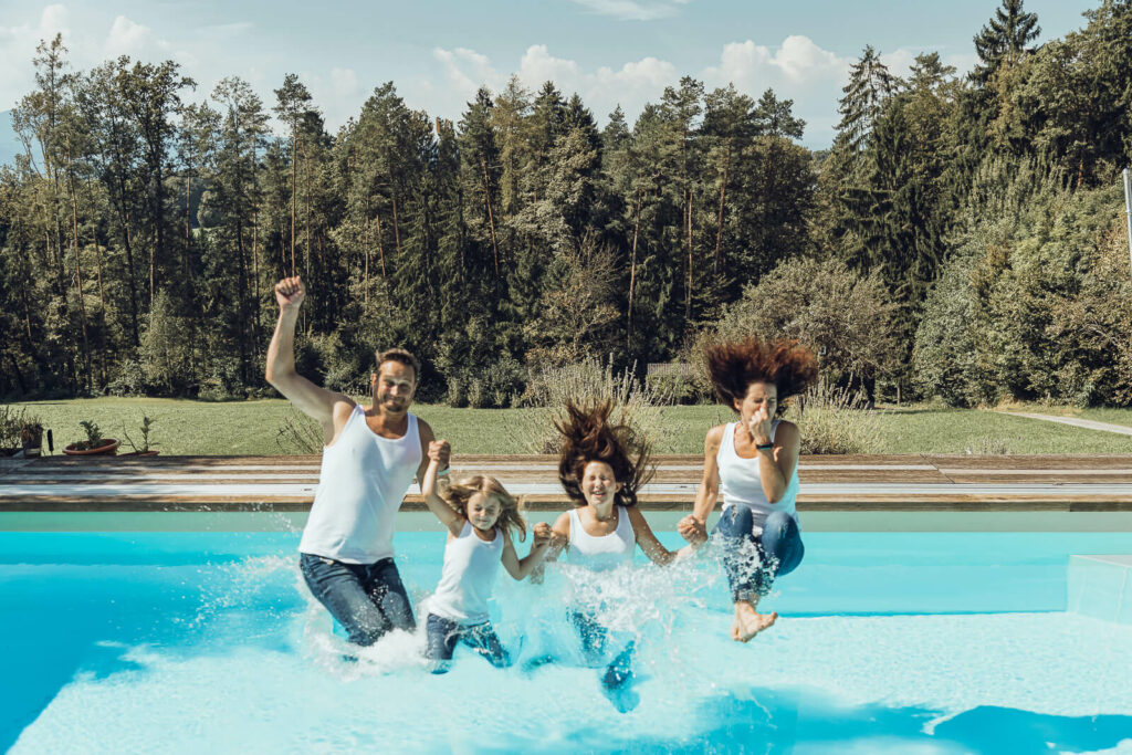 Familienfotografin Weiz, Gleisdorf und Hartberg, Familie springt mit Kleidung in den Pool